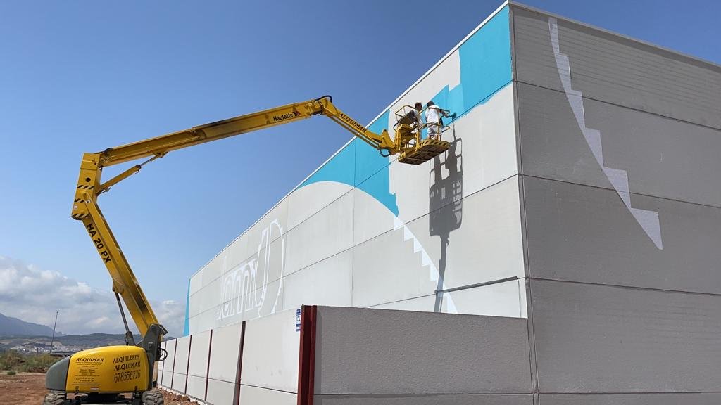 Plataforma elevadora rotulando en altura la fachada de una nave industrial