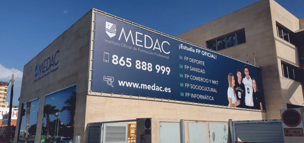 Lona publicitaria de gran formato con ojales en la fachada de MEDAC