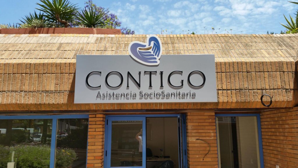Rótulo de bandeja con letras en relieve en la fachada de Contigo Asistencia Sociosanitaria