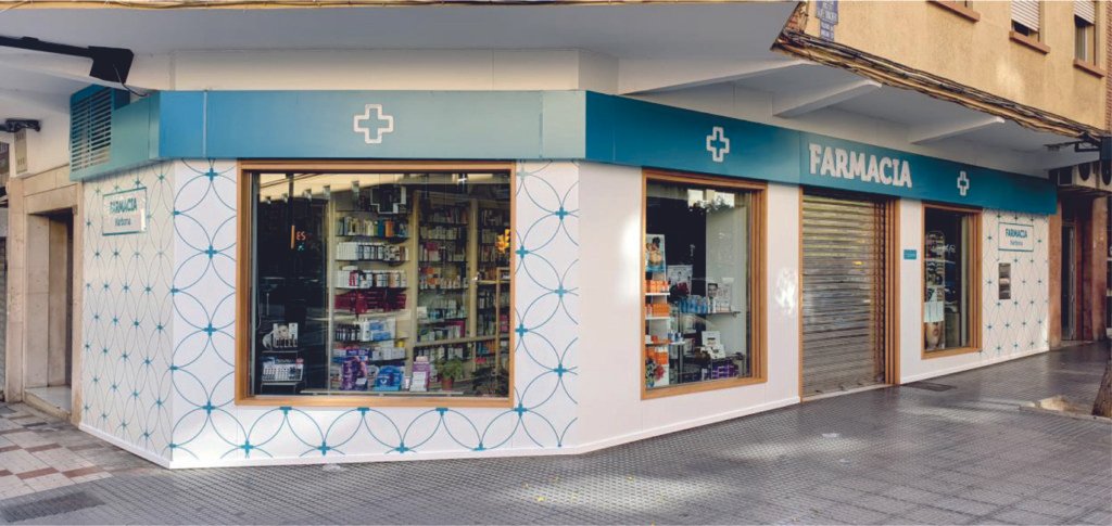 Fachada de farmacia con rótulo y cruces en la marquesina