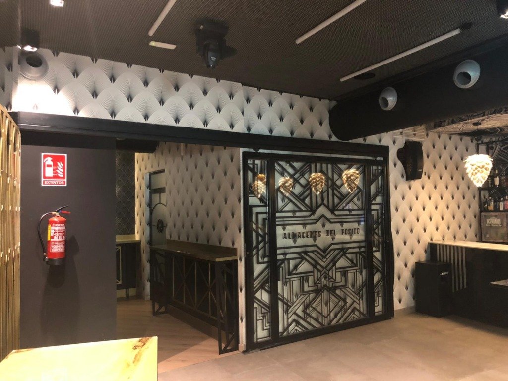 Puerta de cristal decorada con vinilo en un salón con paredes capitonadas